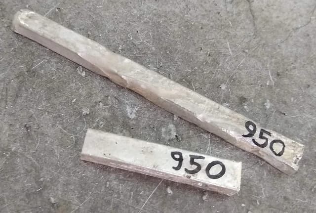 Two 950 silver ingots lying on a grey surface.