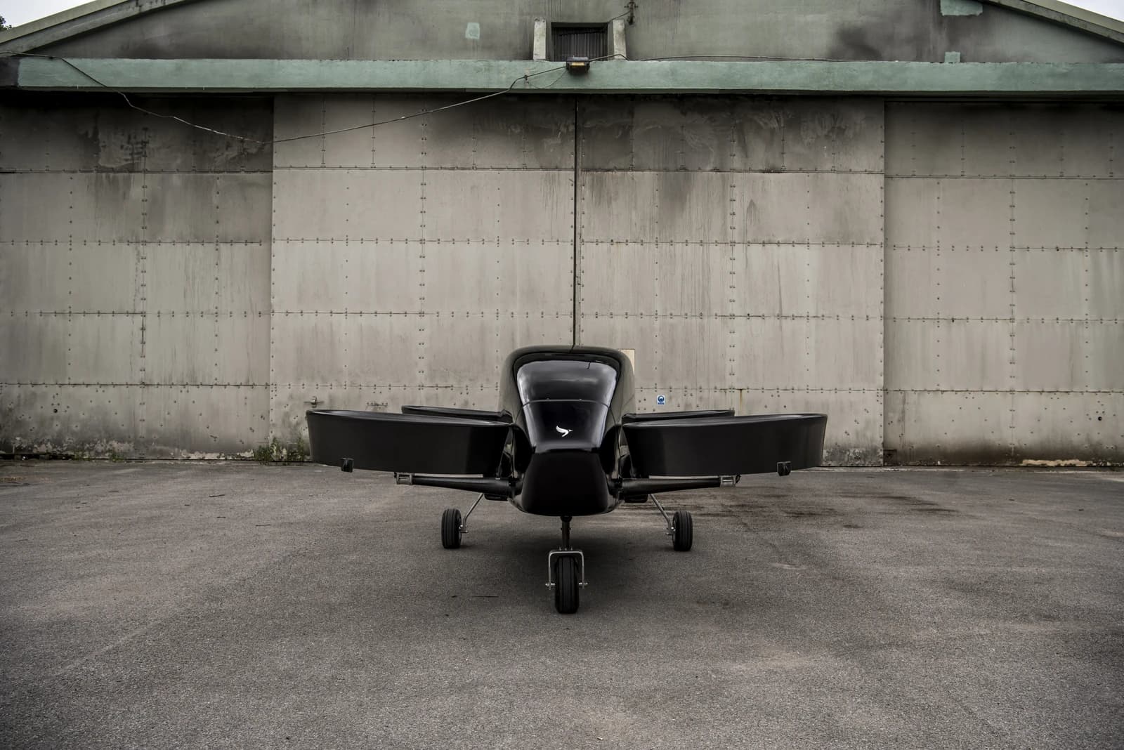 Vertical Aerospace Proof of Concept aircraft in front of a large hangar building.