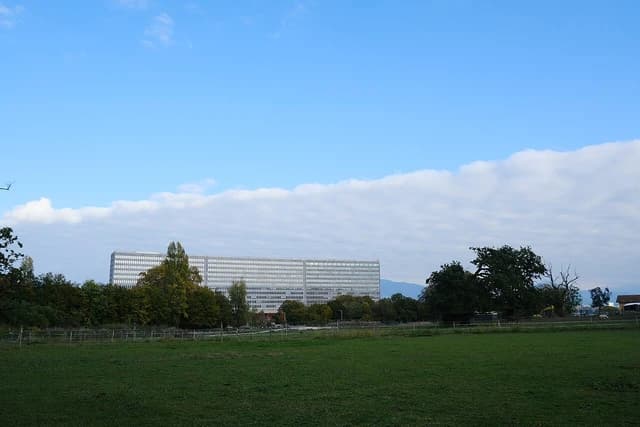International Labor Office building in Geneva, Switzerland, surrounded by trees and a green field.