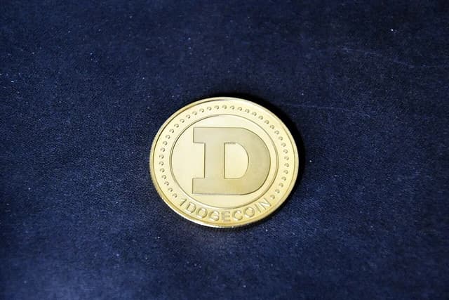 Physical gold Dogecoin cryptocurrency coin displayed on a black surface.