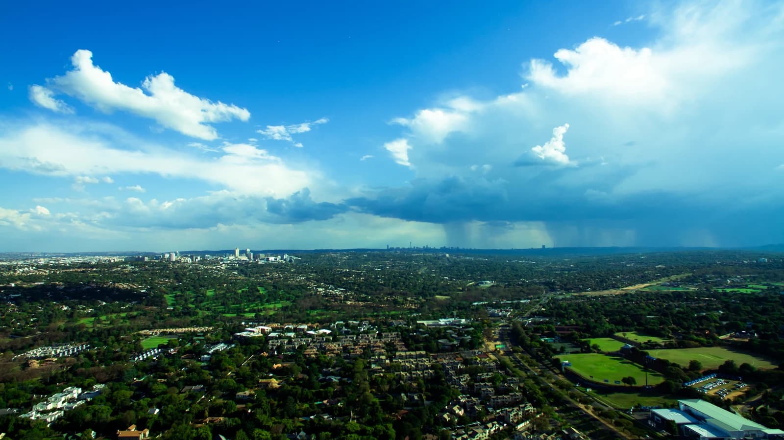 Aerial panoramic view of Johannesburg, South Africa, under a partially cloudy sky.