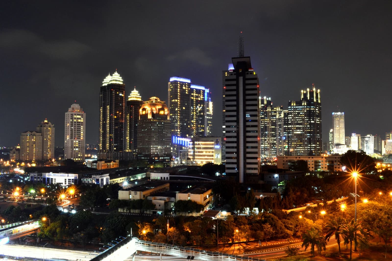 Nighttime city skyline of Jakarta, Indonesia, showing illuminated skyscrapers and streets.