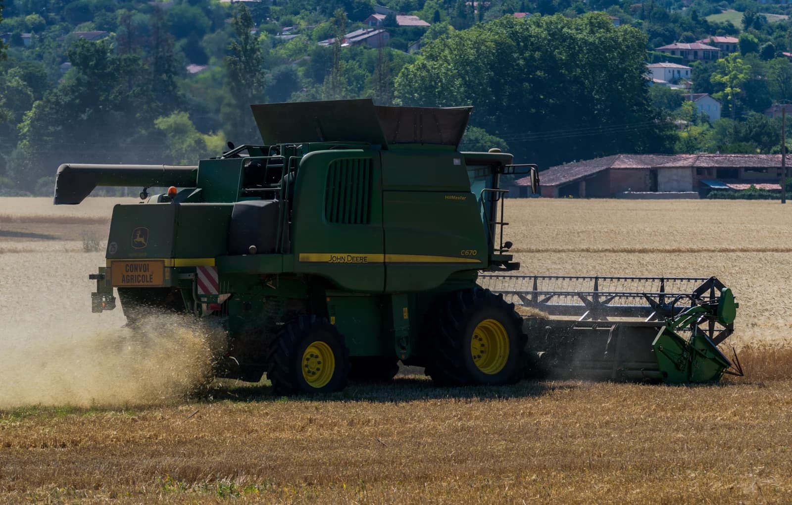 John Deere combine harvester working in a wheat field in rural France.