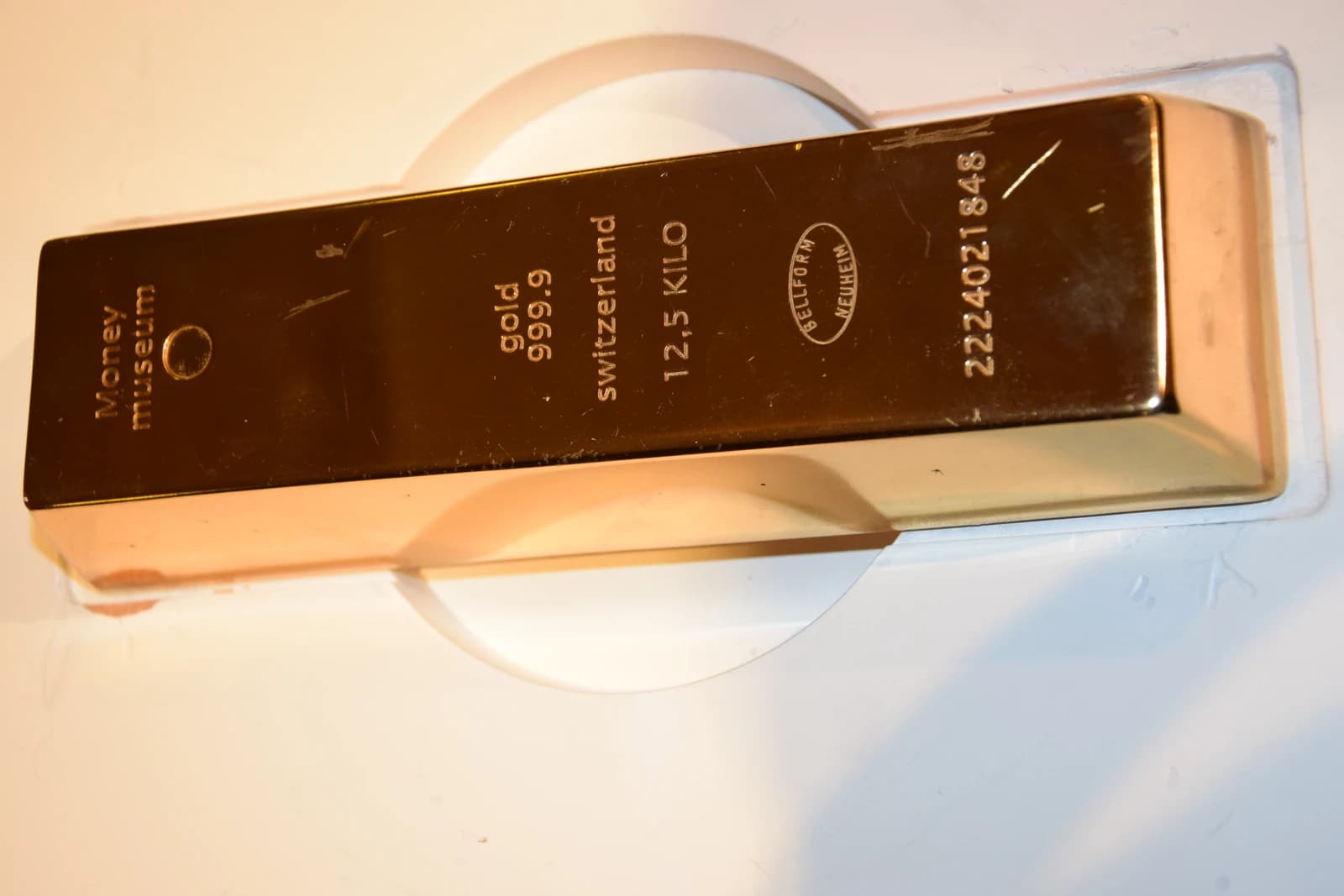 Close-up of a gold bar with engravings on a display stand.