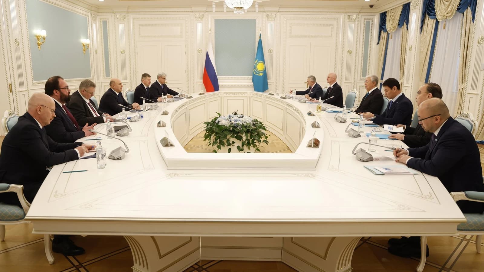 Mikhail Mishustin and Kassym-Jomart Tokayev with officials at a large table.