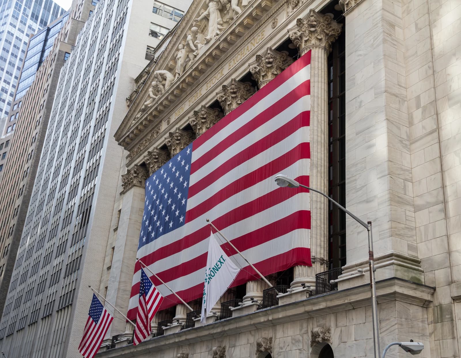 Large American flag hanging on the front of the New York Stock Exchange building.