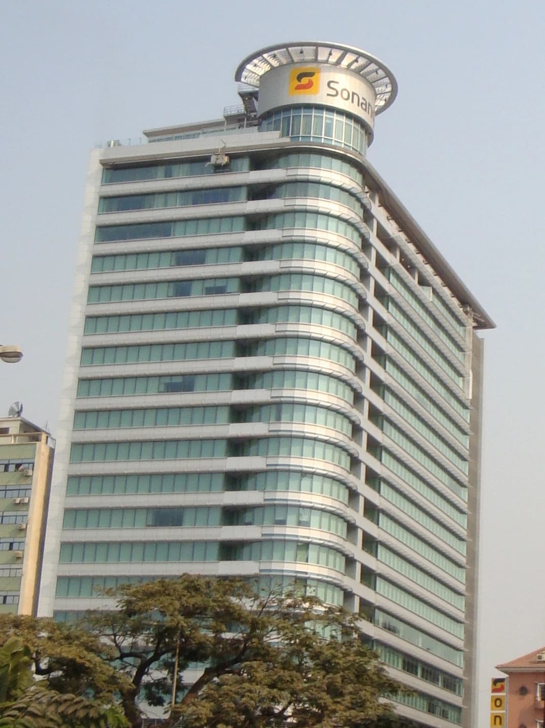 Exterior view of the Sonangol building, a tall corporate structure with curved glass windows.