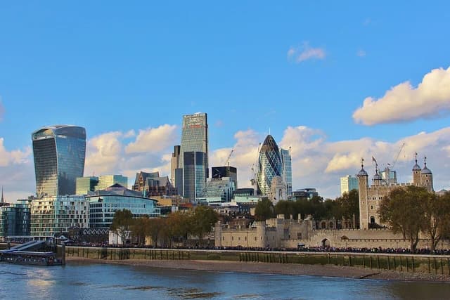 Skyline of The City of London's financial district with modern buildings and Tower of London.