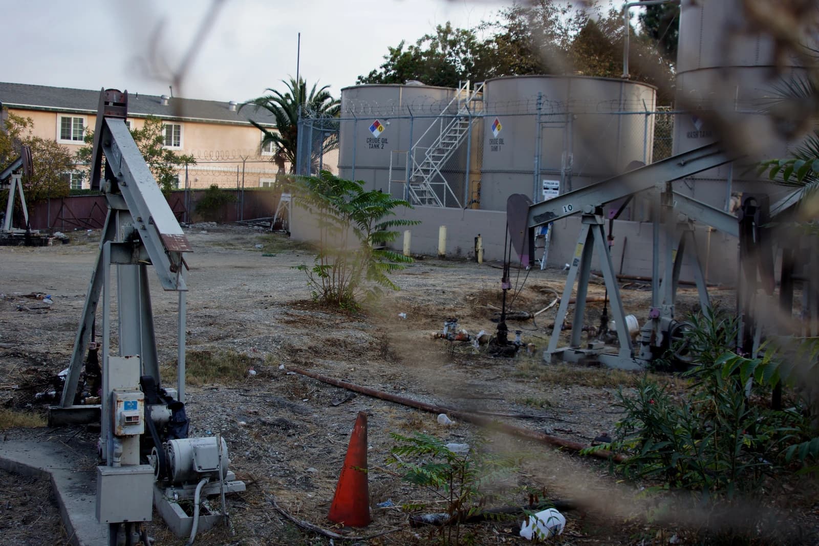 Oil jack pumps operating near large crude oil storage tanks and residential buildings.