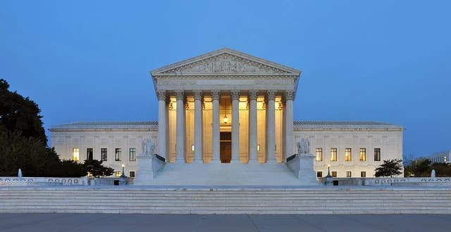 The United States Supreme Court Building illuminated at dusk.