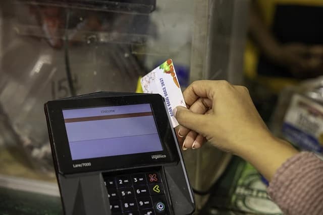 Customer inserting a WIC program benefit card into a payment terminal at checkout.