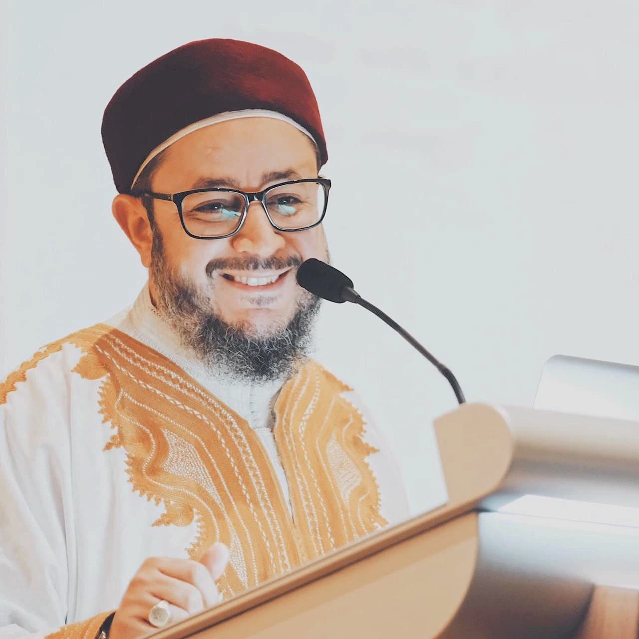 Shaykh Ahmed speaking at a podium with a microphone in Singapore.