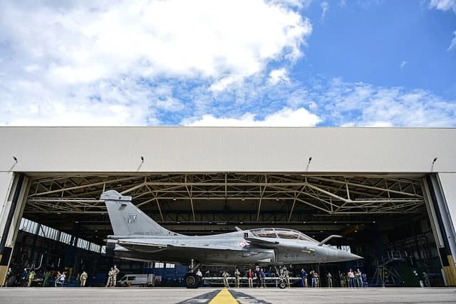 French Rafale fighter jet parked outside a hangar at an air base.