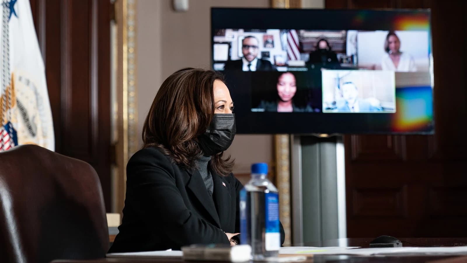Kamala Harris, Vice President, sits at a table and looks towards a monitor showing a video conference.