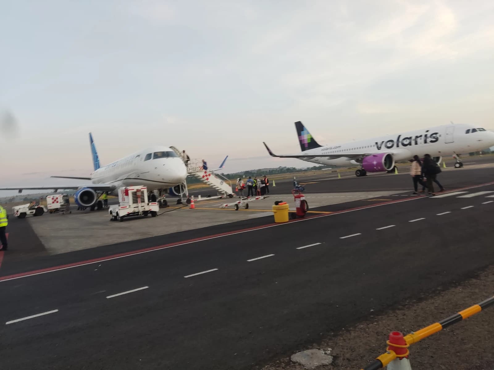 Volaris A320-271N (XA-VRQ) aircraft with passengers walking nearby on the tarmac at MLM airport.