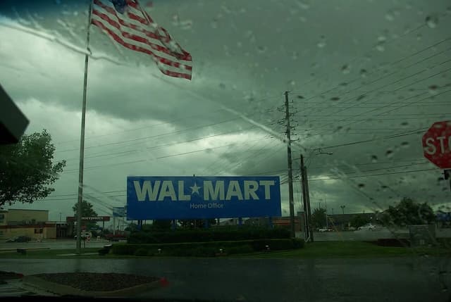 Sign for Walmart Home Office in Bentonville, Arkansas, with American flag and stormy sky.