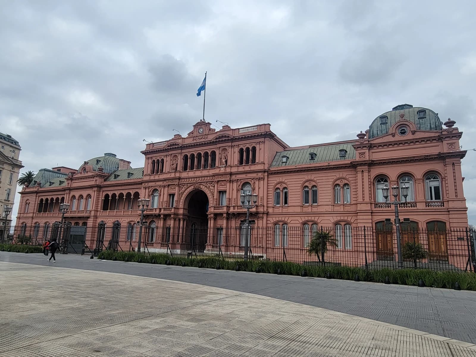 La Casa Rosada, the presidential palace of Argentina, stands under a cloudy sky.