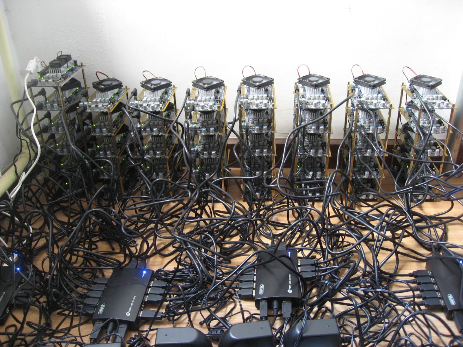 Bitcoin mining rig components with circuit boards, fans, and numerous connecting wires.