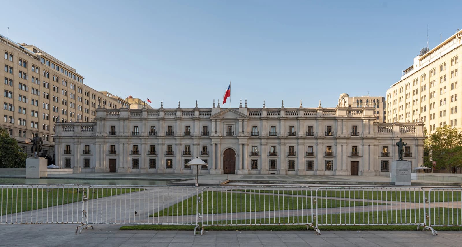 The Palacio de La Moneda, a large white building with many windows, under a clear sky.