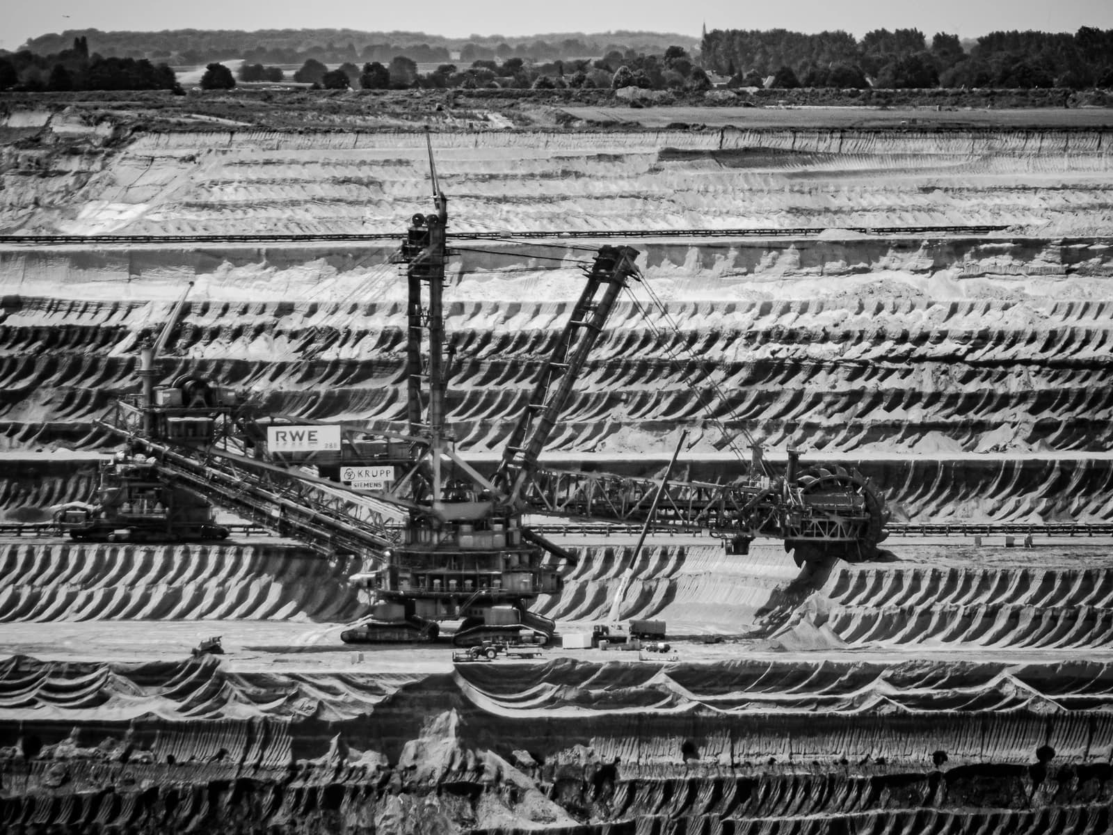 Massive bucket-wheel excavators working in an open-pit lignite mine, with terraced layers of earth.