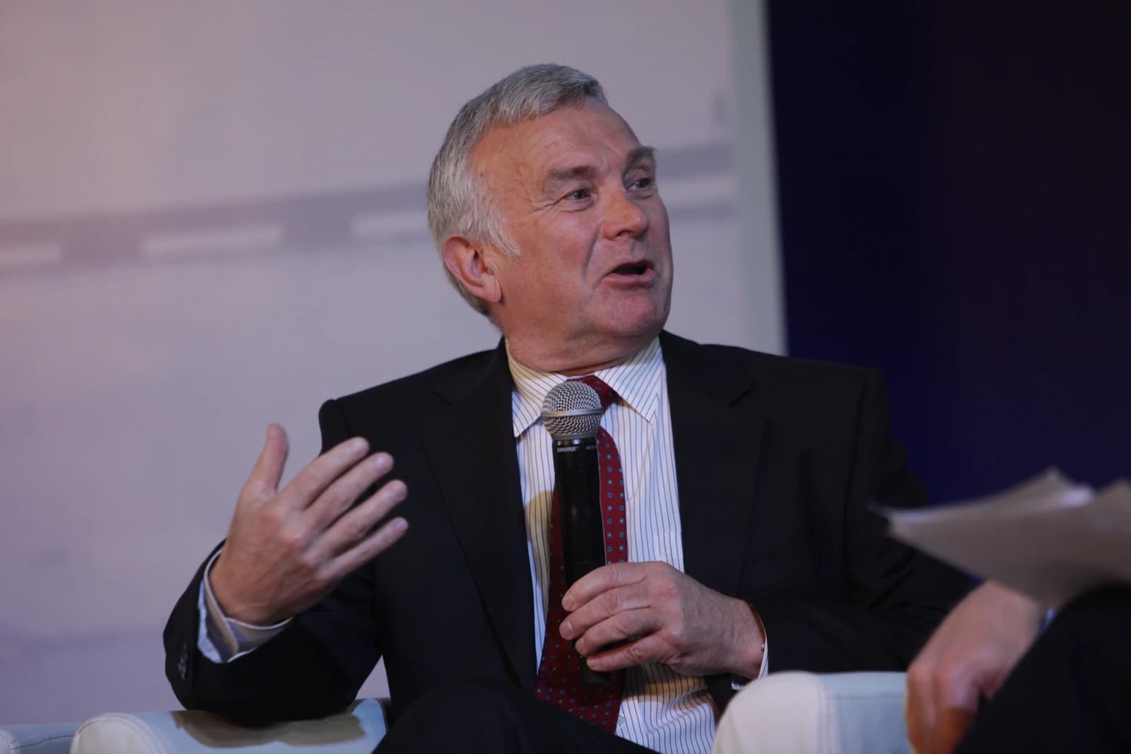 John Walker, Chairman of Oxford Economics, speaking into a microphone at an event.