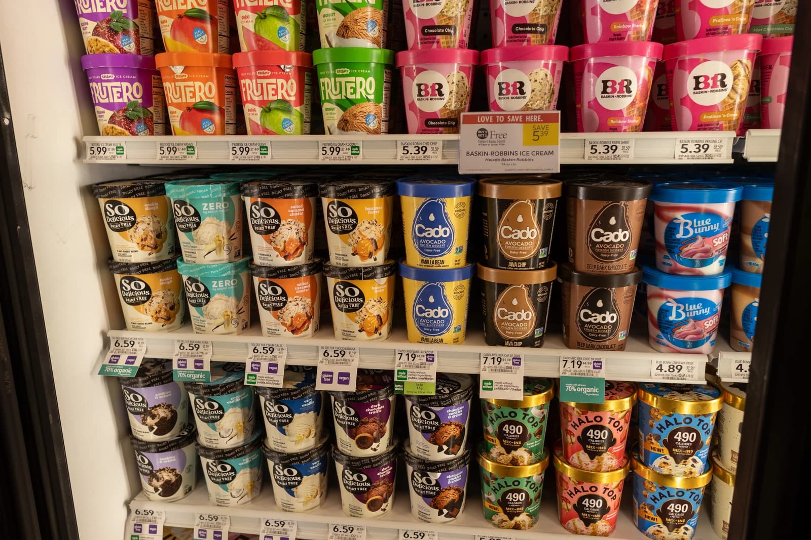 Various brands of ice cream and frozen desserts line a supermarket freezer shelf.