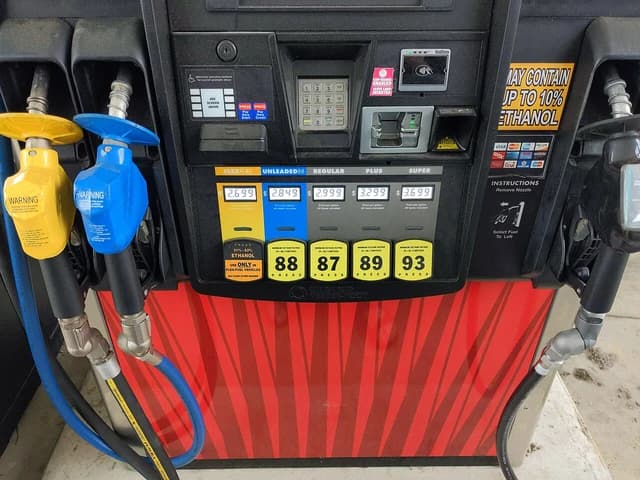 Close-up of a gas pump with various fuel grades and prices displayed.