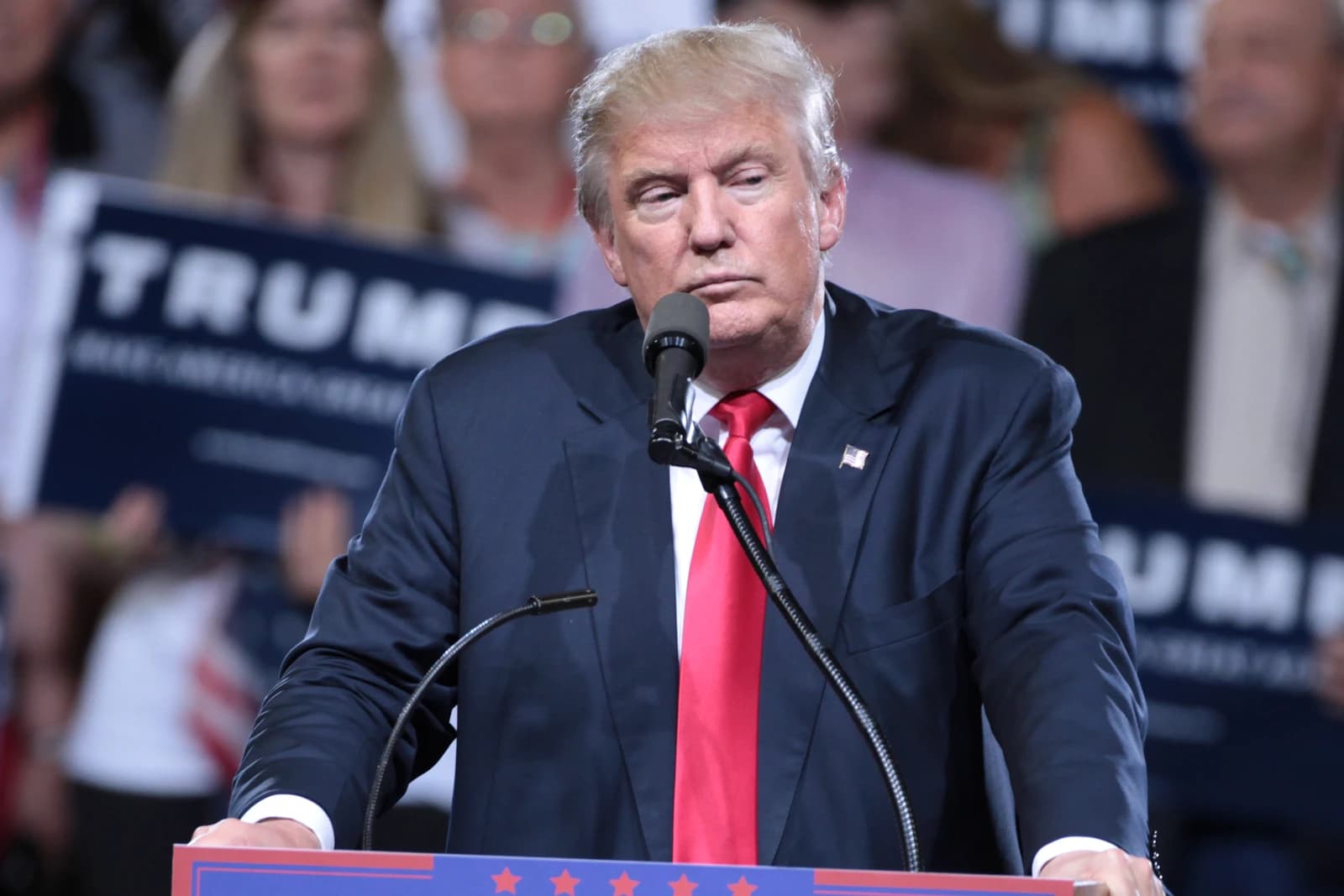 Donald Trump speaking from a podium with several microphones.