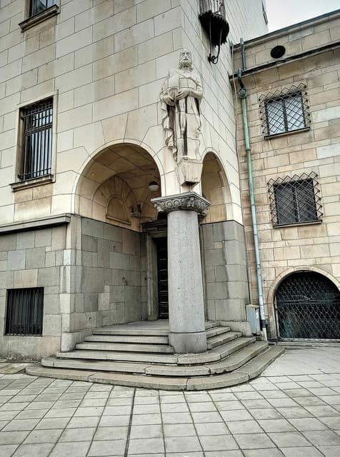 Exterior view of the Bulgarian National Bank central building with a statue and arched entrance.