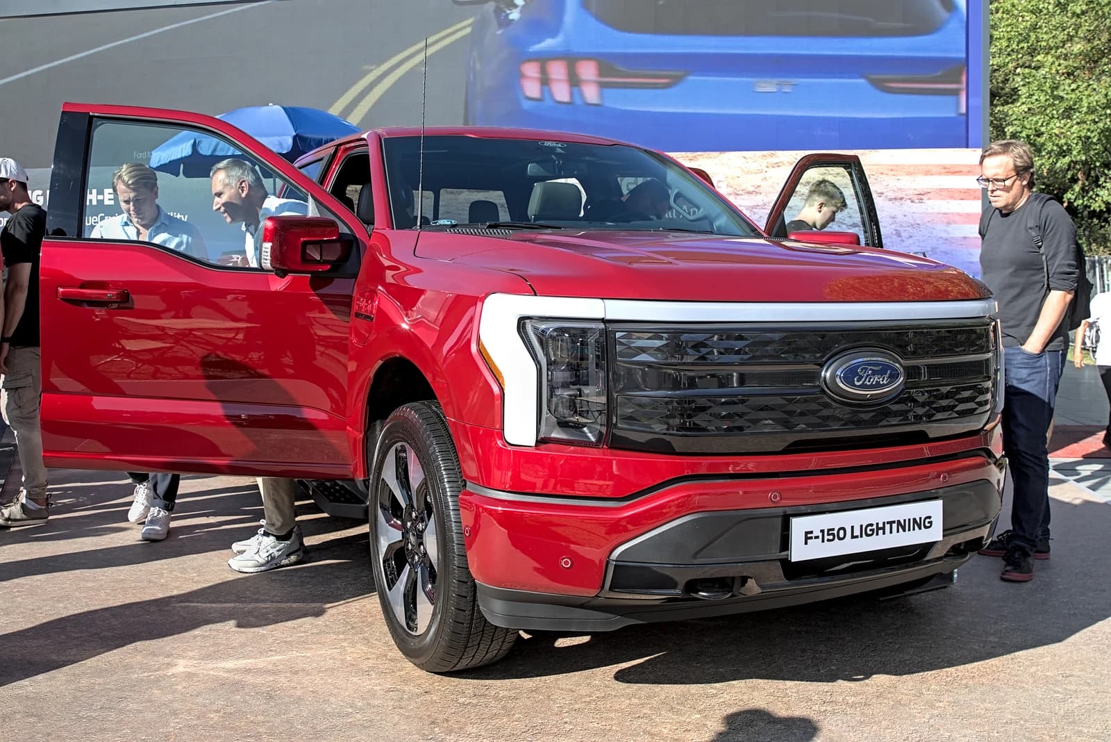 Red Ford F-150 Lightning electric pickup truck on display at an auto show.