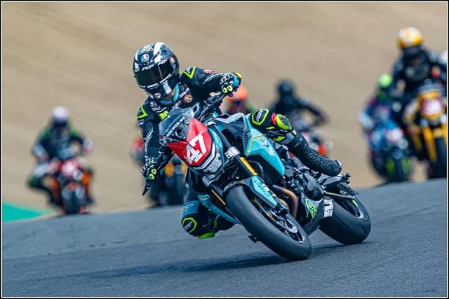 Richard Cooper, FHO Racing BMW Motorrad rider, leans into a turn on a racetrack.