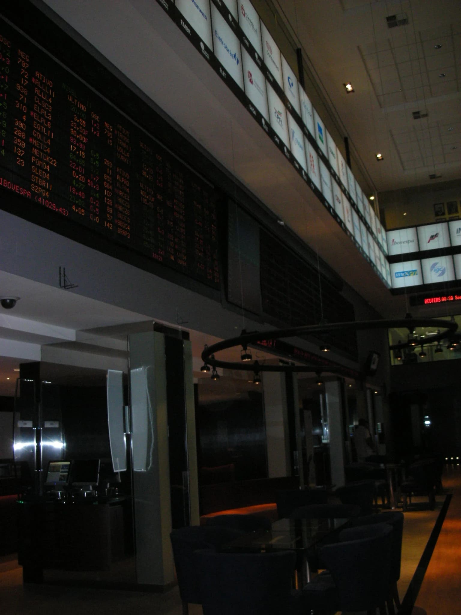 Financial data and stock tickers displayed on a large screen inside a stock exchange building.