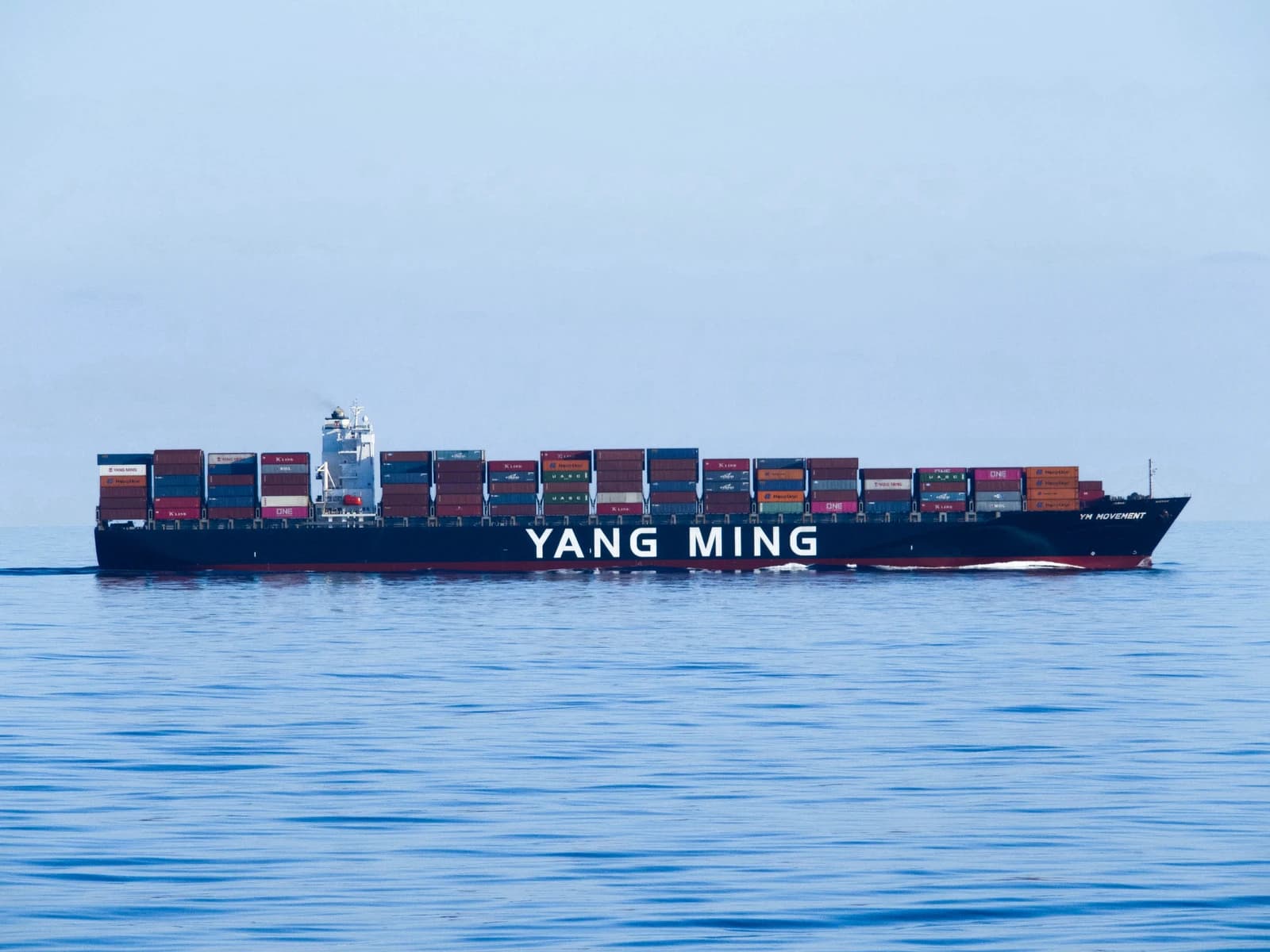 Yang Ming container ship with stacked containers sailing in open water.