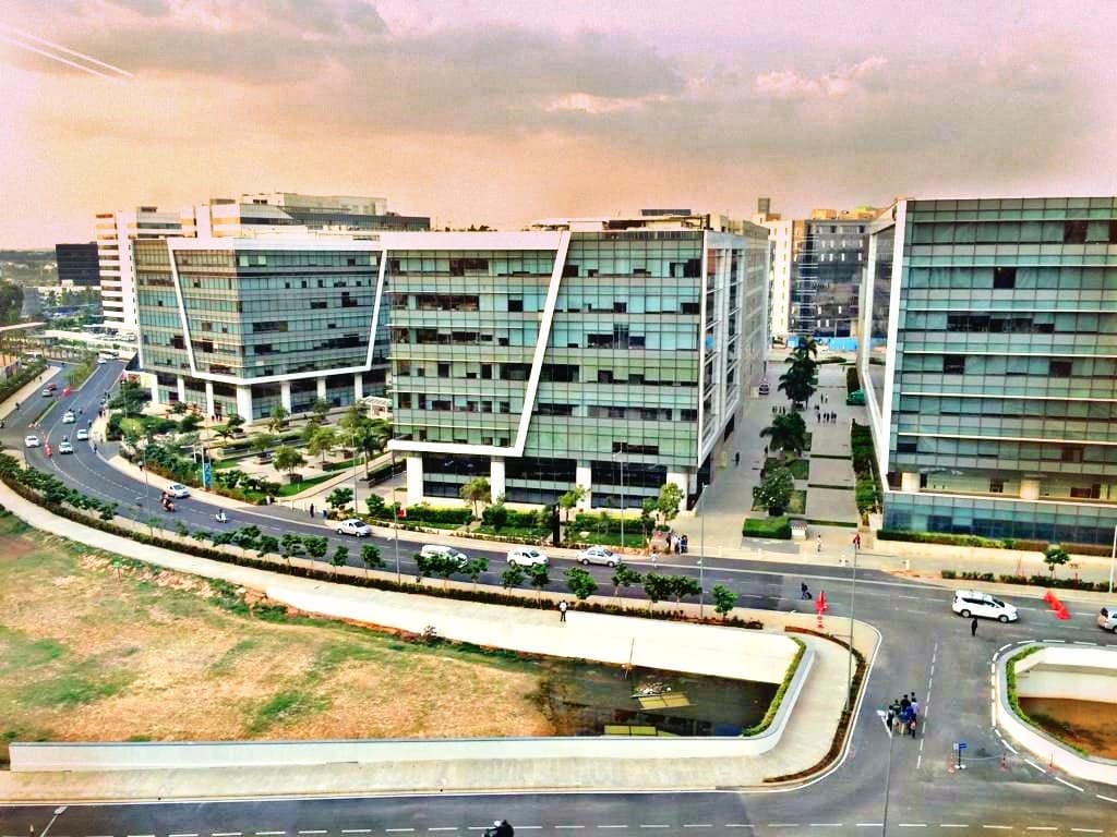 An overhead view of multiple modern glass office buildings and roads at Embassy Tech Village.