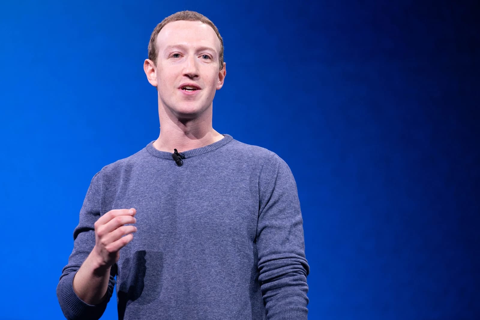 Mark Zuckerberg, CEO of Meta, speaking at a conference with a blue background.