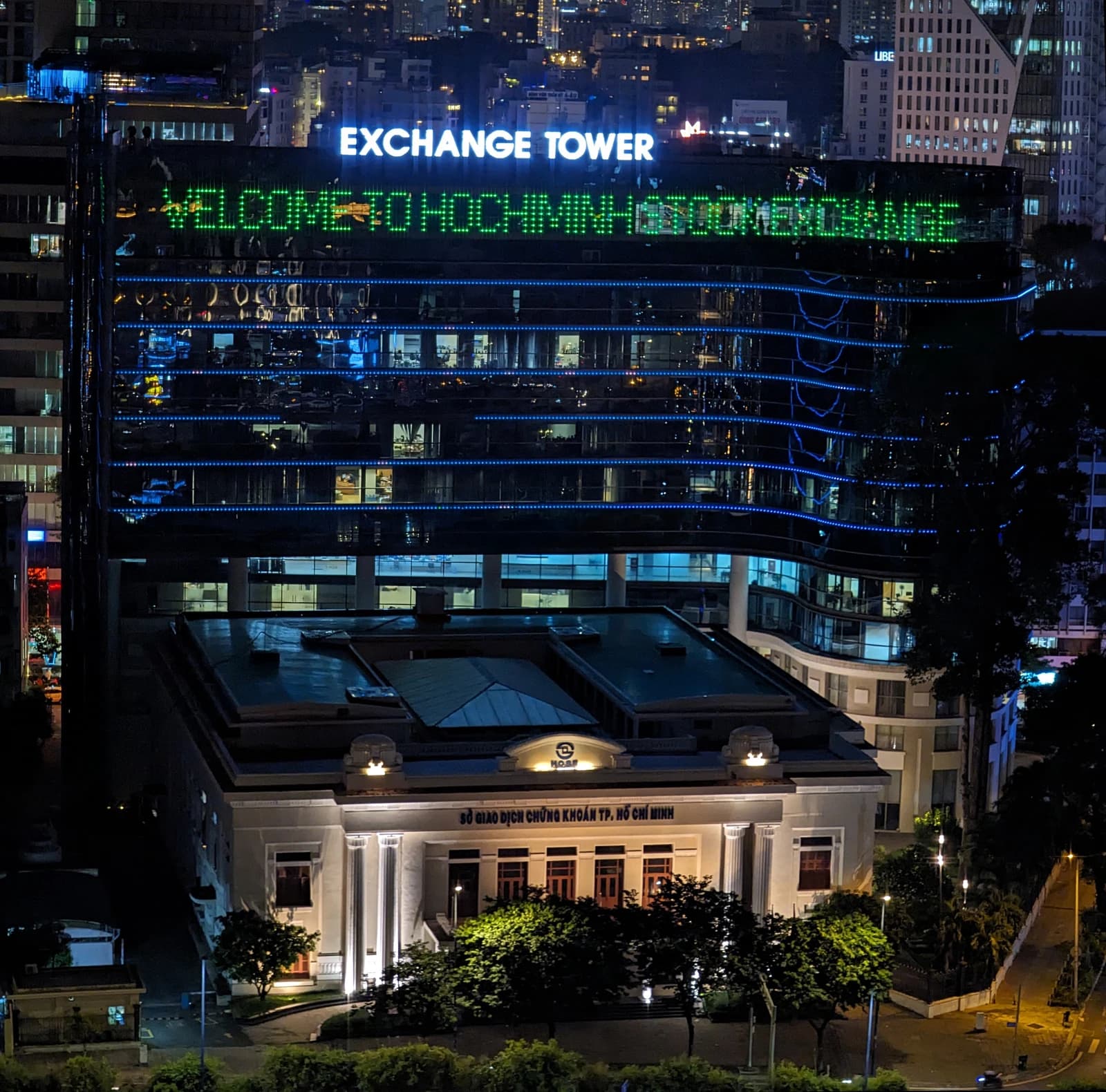 The Ho Chi Minh Stock Exchange building at night with the lit 'Exchange Tower' sign above.