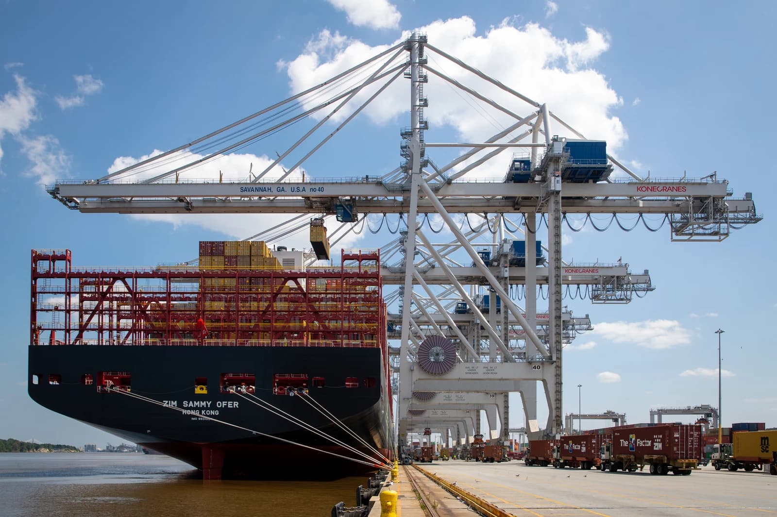 Large container ship being unloaded by cranes at a busy port terminal.