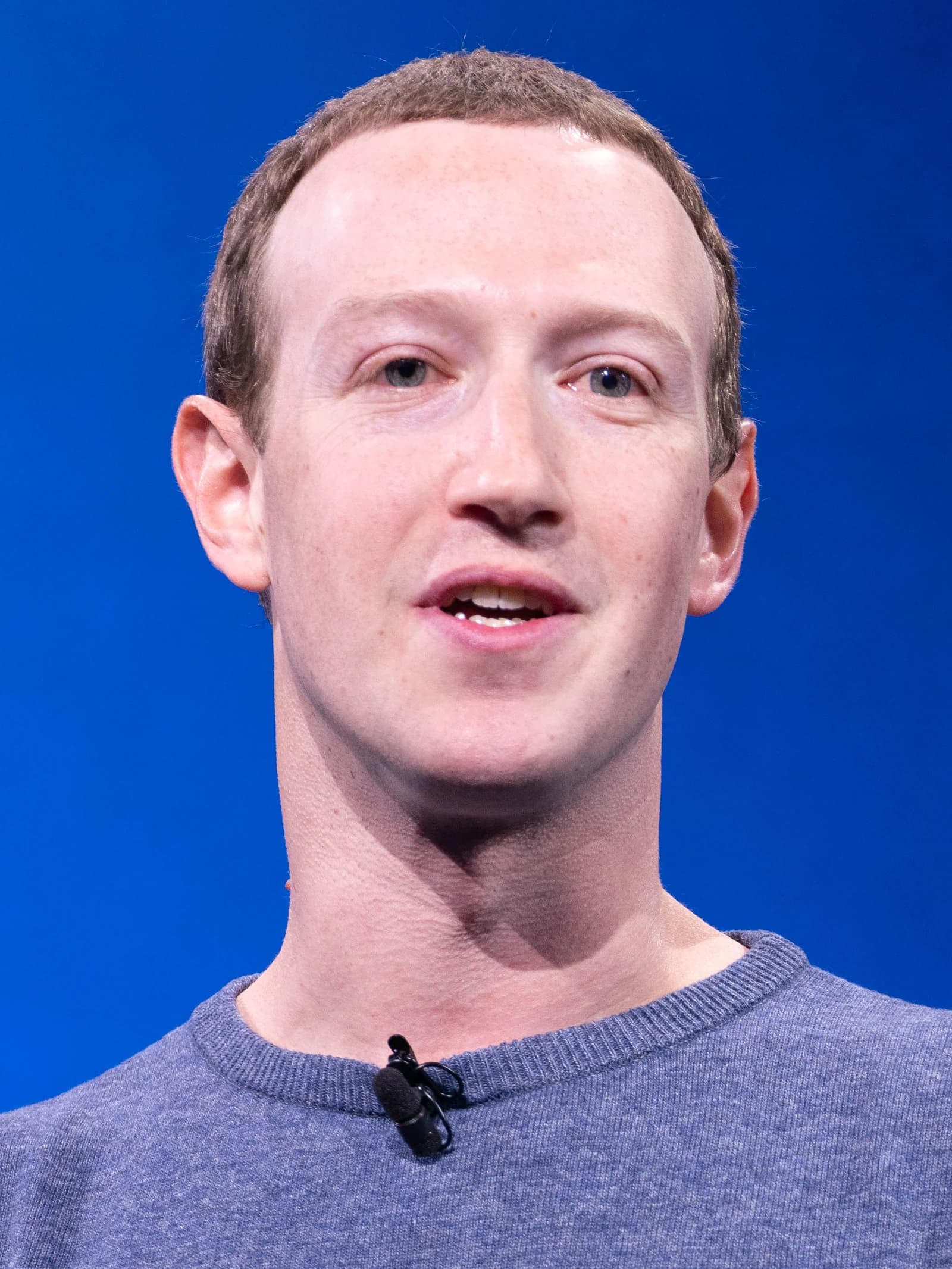 Mark Zuckerberg, CEO of Meta, speaking at a conference with a blue background.