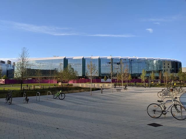 AstraZeneca headquarters building in Cambridge, UK with construction equipment visible.