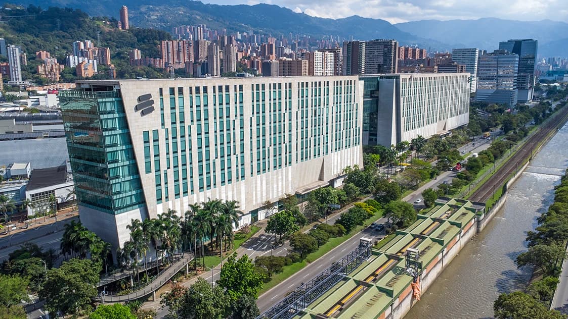 Bancolombia building in Medellin, Colombia, alongside a river and railway tracks.