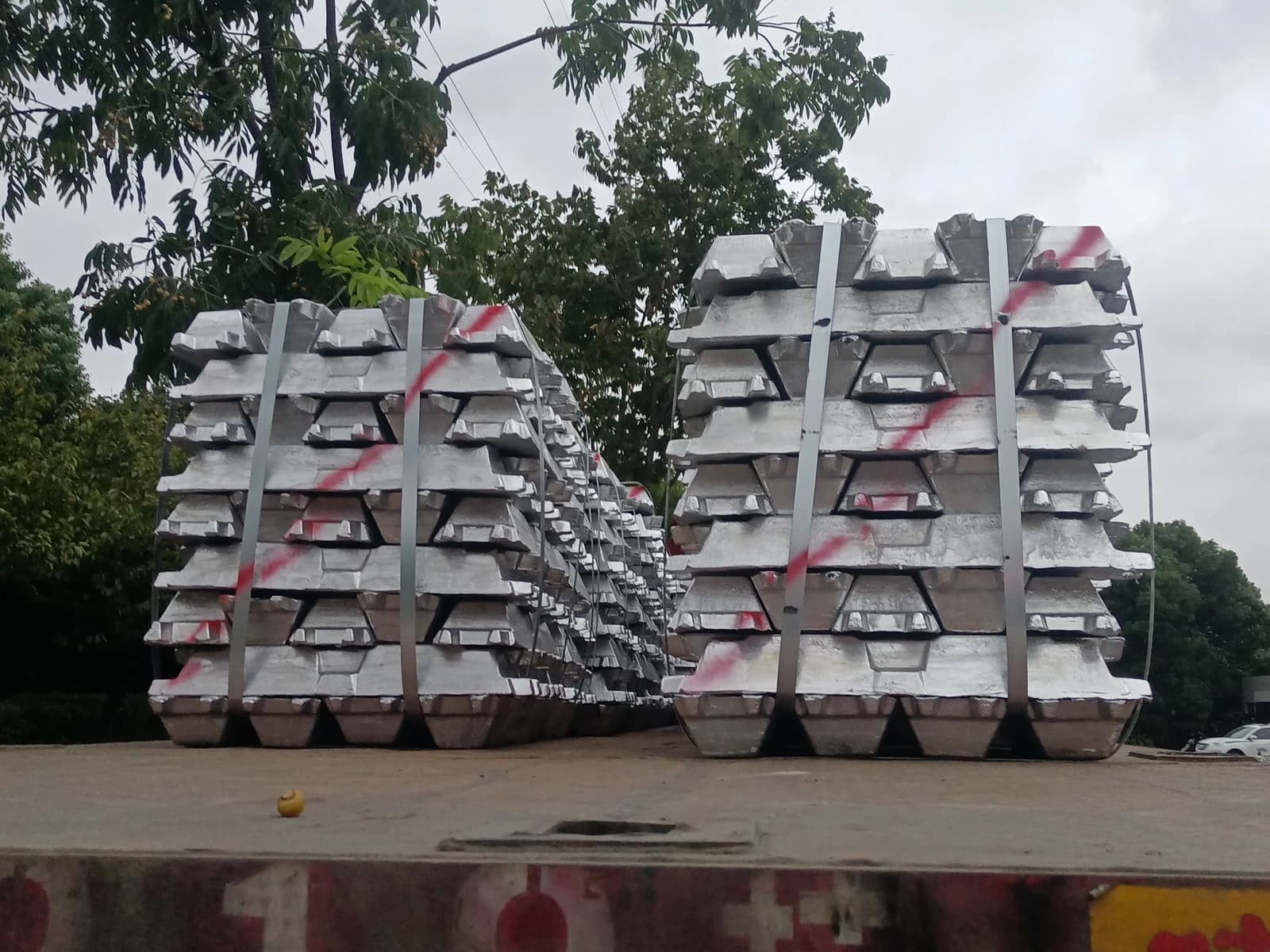 Aluminum ingots, stacked and secured, loaded on a truck bed outdoors.