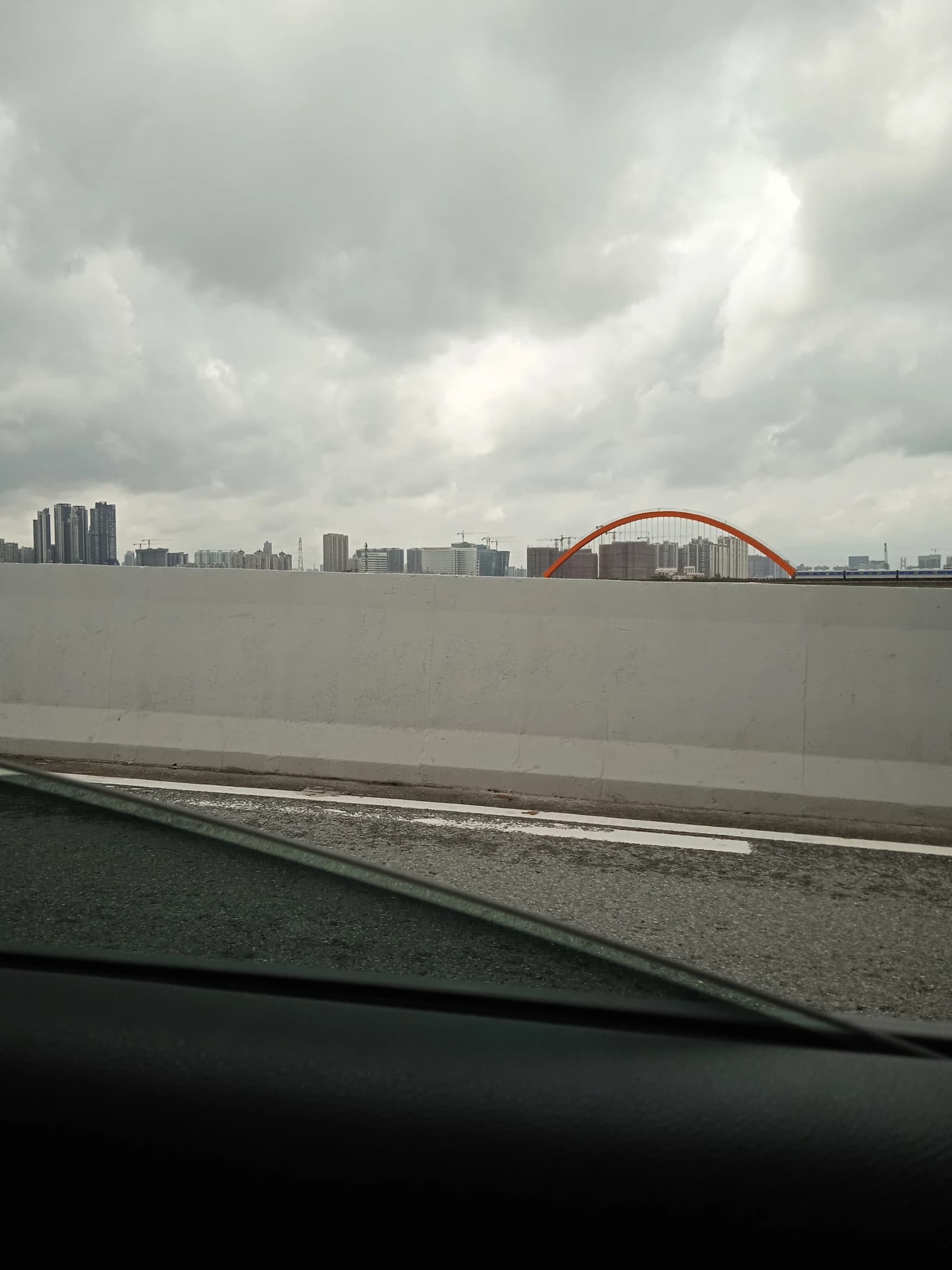 Skyline of Guangzhou's Liwan Datansha district, residential buildings, and an orange arch bridge.