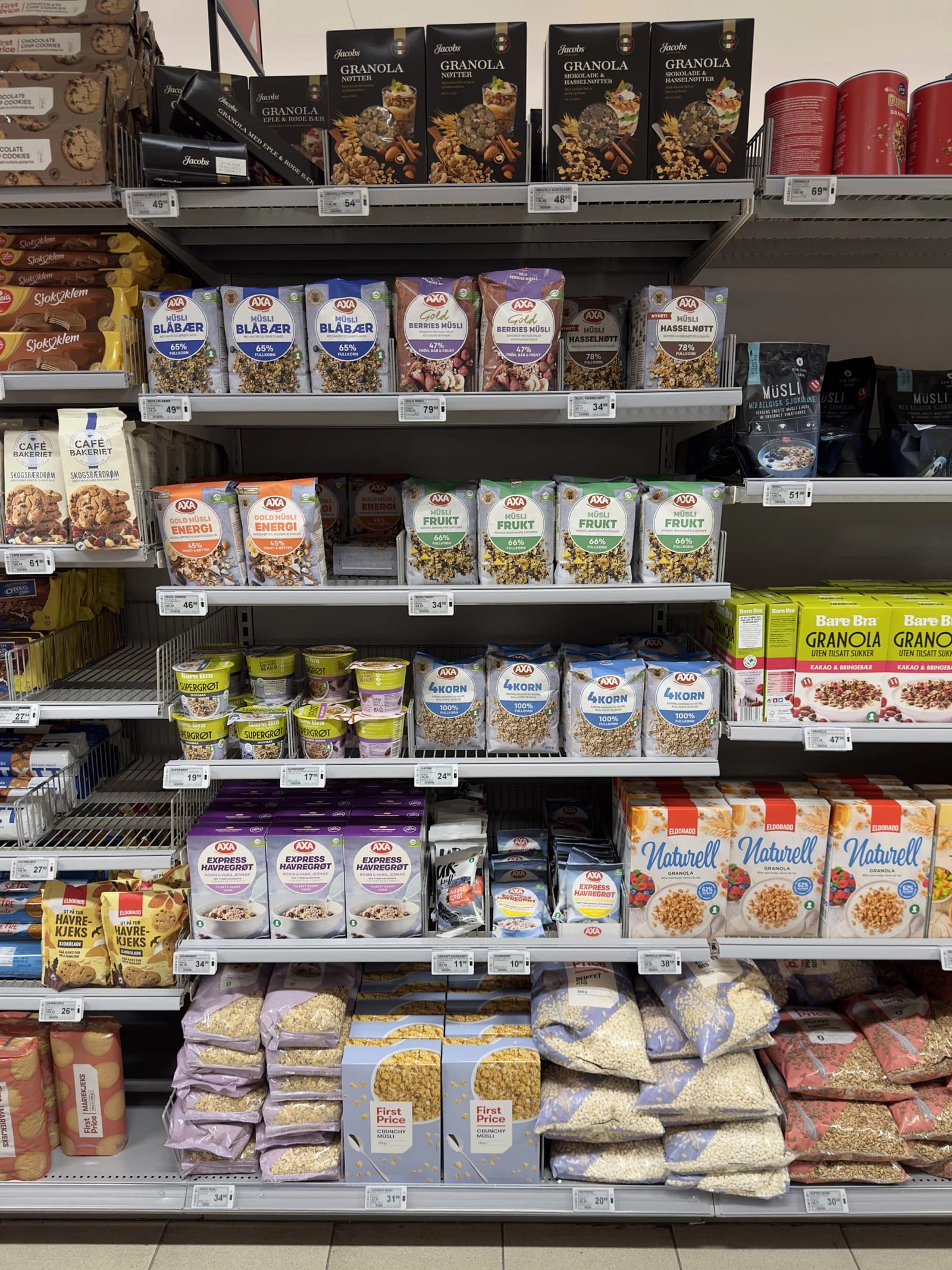 Grocery store aisle shelves displaying rows of breakfast cereals, oatmeal, and granola products.
