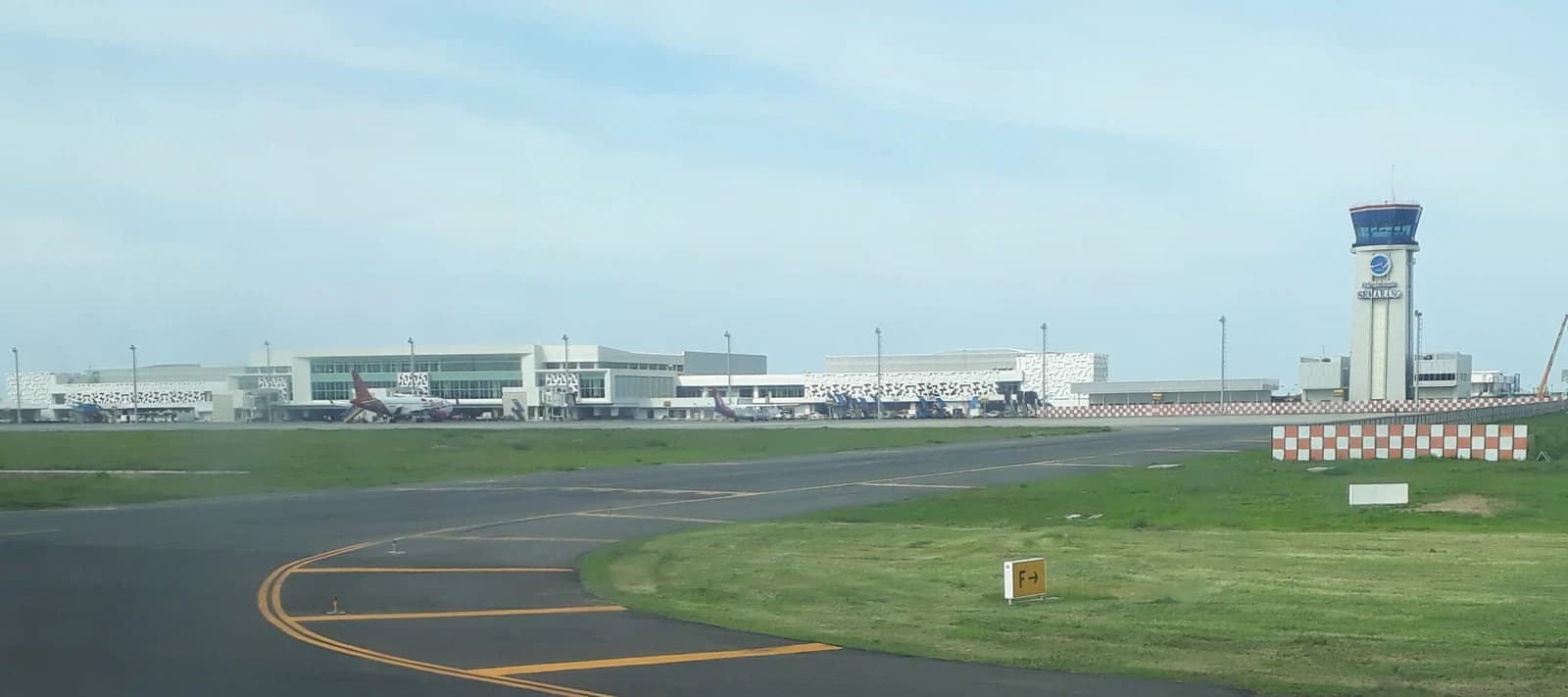 Semarang Airport terminal building, control tower, and parked aircraft visible from the runway.