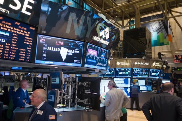 Traders work at desks on the New York Stock Exchange trading floor.