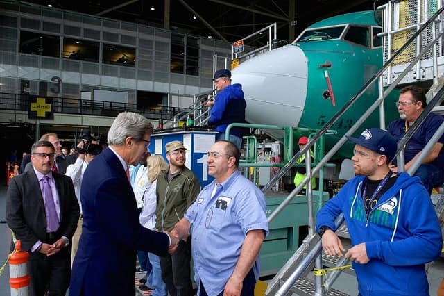 Secretary John Kerry shaking hands with a Boeing factory worker.