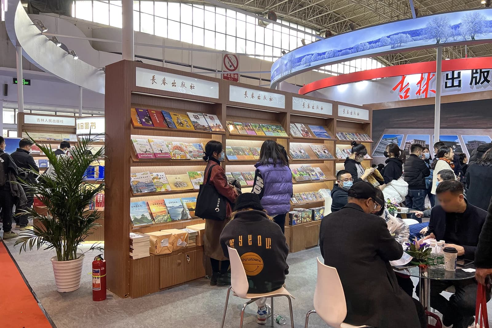 People browse books displayed on shelves at the Changchun Publishing House booth.