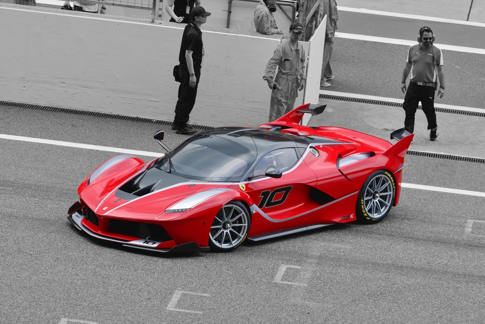 Ferrari FXX-K, a red and black track car, on a race circuit with several personnel.