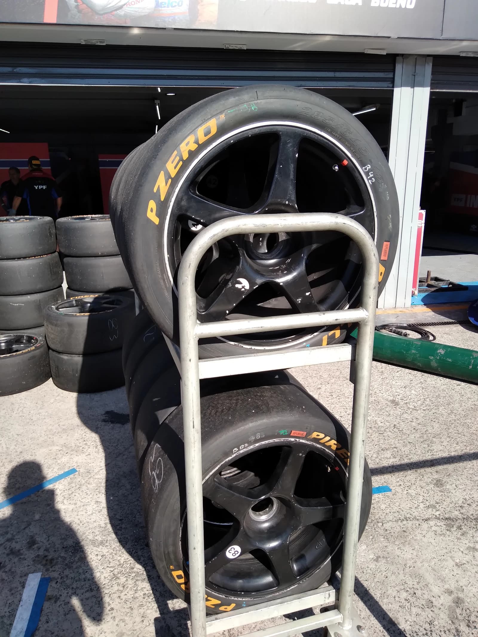 Pirelli P Zero tires stacked on a metal rack in a garage or pit area.