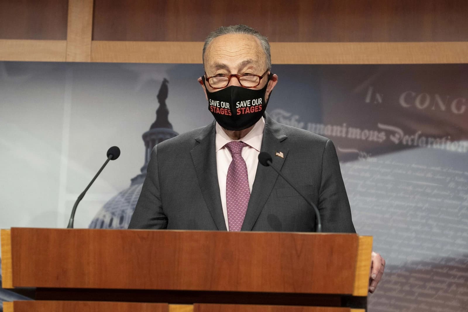 Senate Majority Leader Chuck Schumer speaking at a podium with microphones.